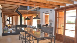 A rustic interior with a wooden ceiling, a glass dining table, and a fireplace. - Can Cortana 005 fantastic finca with private swimming pool, children's area, ping pong and air conditioning (Llubi)