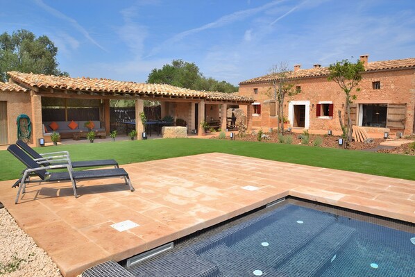 A pool area with lounge chairs and a covered patio. - Can Cortana 005 fantastic finca with private swimming pool, children's area, ping pong and air conditioning (Llubi)