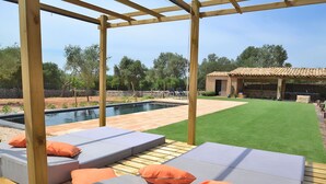 A poolside area with lounge chairs and a pergola structure. - Can Cortana 005 fantastic finca with private swimming pool, children's area, ping pong and air conditioning (Llubi)