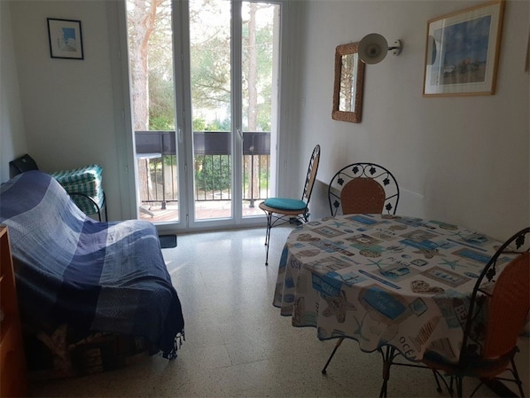 Quarto com cama, cadeira, mesa com toalha e janela com vista para o exterior.