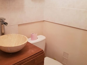 Um banheiro com toucador de madeira, vaso sanitário e rolo de papel higiênico.