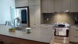 A modern kitchen with stainless steel appliances, a large island, and a built-in oven. - New beautiful 2 Bedroom Unit in Biltmore District Walk to Shopping Restaurants (Phoenix)