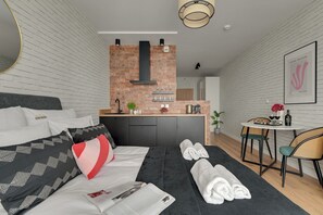 A modern hotel room with a sofa, a dining area, and a kitchen. - Bastion Wałowa City Center by Downtown Apartments (Gdansk)