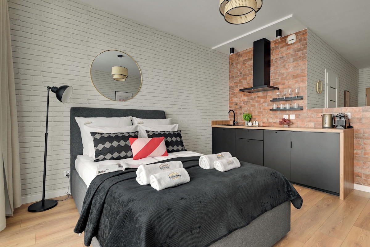 A modern bedroom with a bed, bedside lamp, and a mirror.