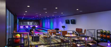 A bowling alley with multiple lanes, seating areas, and a bar.