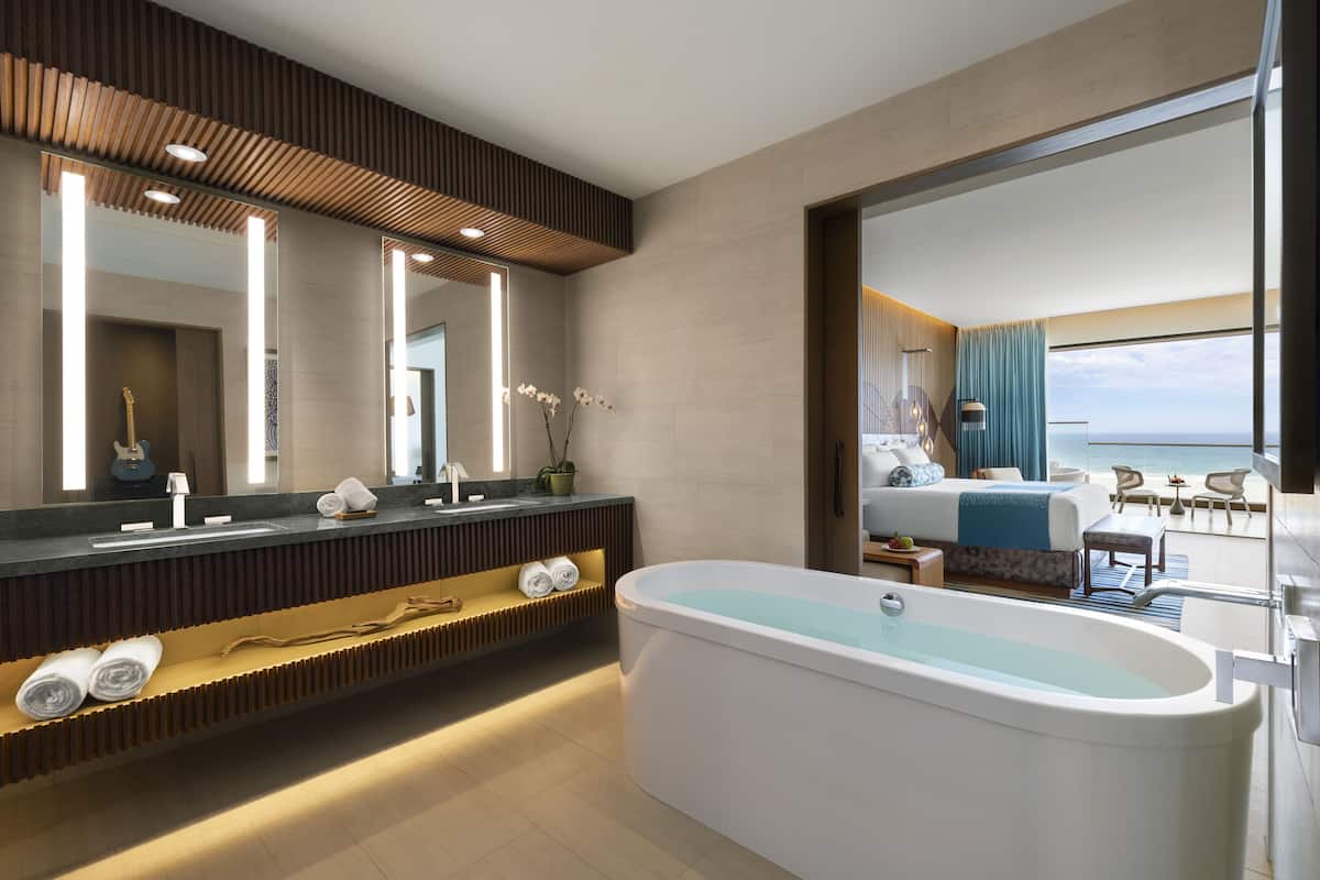 A modern bathroom with a freestanding bathtub, a large mirror, and a vanity with a built-in shelf.
