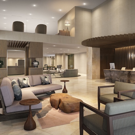 A spacious lobby with a modern reception desk, seating area, and a large window.