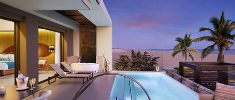 Una suite de hotel moderna con piscina privada, sillones de descanso y un hogar para fogata.