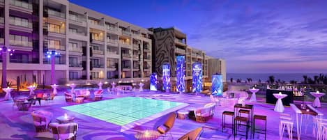 A rooftop bar with a pool table, lounge chairs, and bar area.