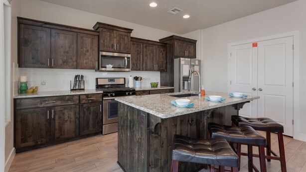 A modern kitchen with dark wooden cabinets, stainless steel appliances, and a central island with bar stools. - Ladera Resort 370, Arcade Basketball, (2) X-Box Ones, and Community Pool (Washington)