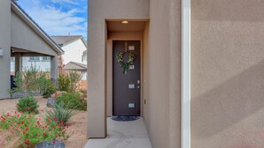 A house entrance with a dark door, a wreath, and a small garden with red flowers and rocks. - Ladera Resort 370, Arcade Basketball, (2) X-Box Ones, and Community Pool (Washington)