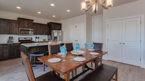 A modern kitchen with dark wood cabinets, a stainless steel microwave, and a dining area with a wooden table set for four. - Ladera Resort 370, Arcade Basketball, (2) X-Box Ones, and Community Pool (Washington)