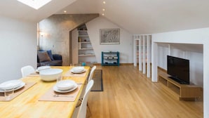 A modern loft apartment with a dining area, a living room with a TV, and a skylight. - Cosy 1 Bedroom Flat in Notting Hill (London)