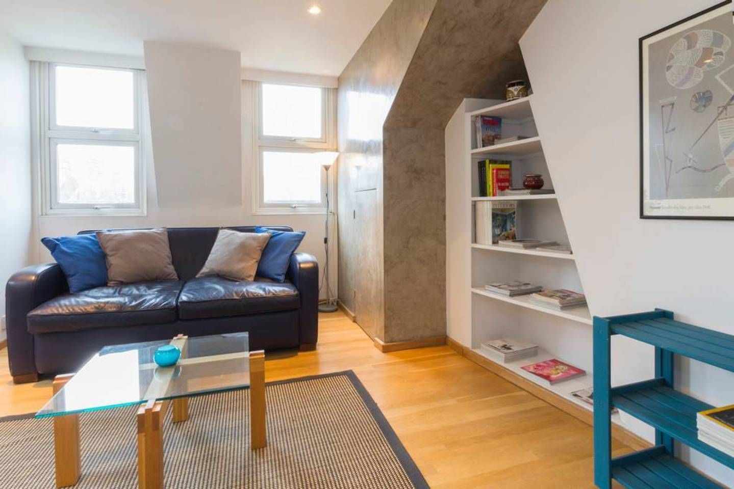 Una sala moderna con un sofá de cuero, una mesa de centro de vidrio y una estantería.