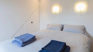 A hotel room with a bed, two wall-mounted lights, and a folded towel on the bed. - Cosy 1 Bedroom Flat in Notting Hill (London)