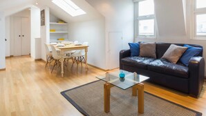 A modern apartment with a dining area, a sofa, and a glass coffee table. - Cosy 1 Bedroom Flat in Notting Hill (London)