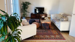 A living room with a sofa, a coffee table, a TV, and a large plant.