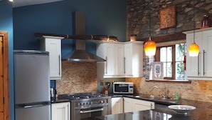 Una cucina moderna con isola centrale, elettrodomestici in acciaio inossidabile e una parete d'accento in pietra.