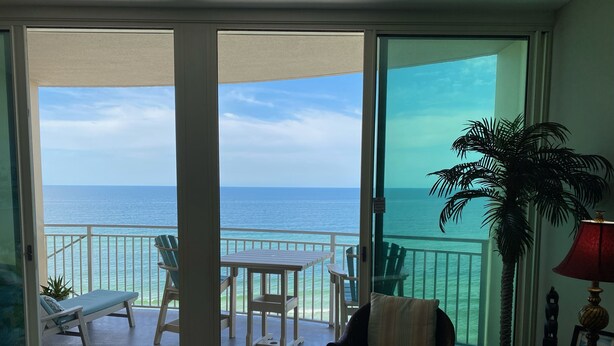 Ein Zimmer mit einer Schiebetür, die auf einen Balkon mit Meerblick führt.