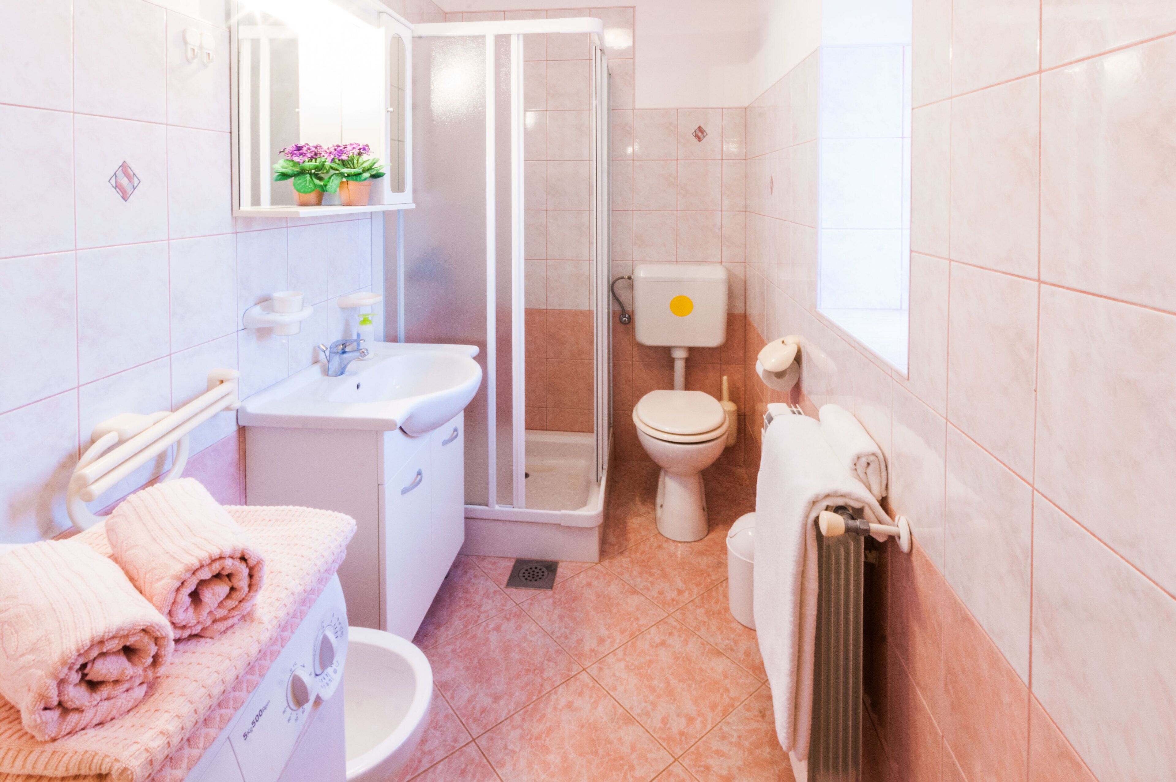 A bathroom with a shower, toilet, sink, and towel rack.