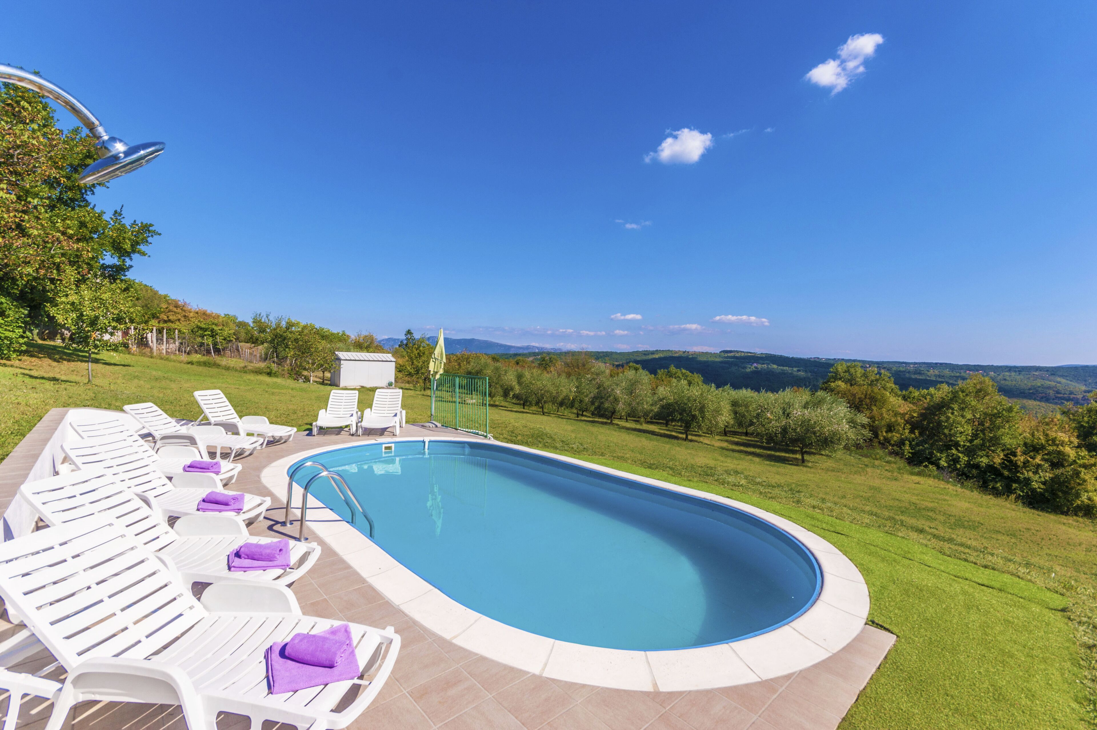 A swimming pool with lounge chairs and a view of the countryside.