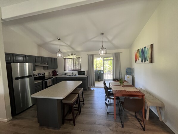 A modern kitchen with a central island, stainless steel appliances, and a dining area with a wooden table and chairs.