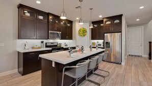 A modern kitchen with dark wood cabinets, stainless steel appliances, and a central island with bar stools. - Paradise Village Resort 86, Private Hot Tub, Game System, Community Amenities, and more (Santa Clara)