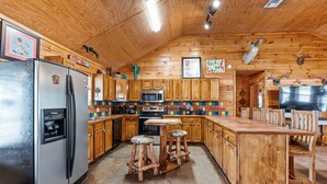 Eine Holzhüttenküche mit Kühlschrank, Mikrowelle und Holzschemeln.