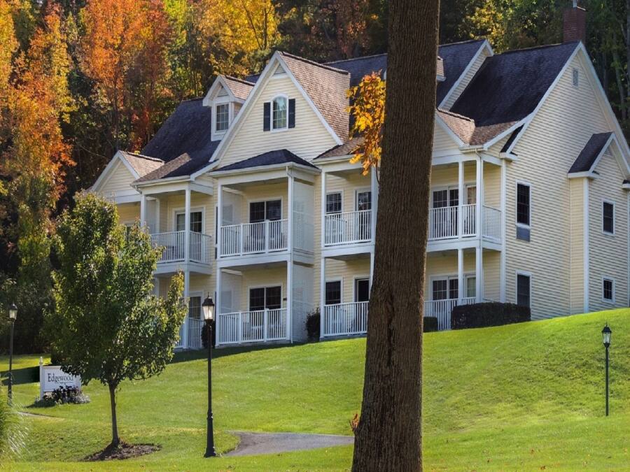 A large, multi-story building with a symmetrical facade, multiple balconies, and a well-maintained lawn.