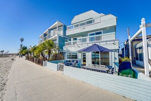 A beachfront hotel with a pool area, outdoor seating, and a view of the ocean.