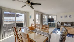 Een ruime woonkamer met balkon, eettafel en televisie.