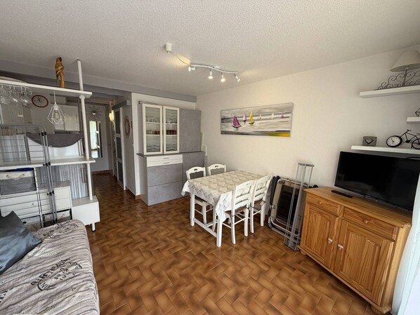 Un espace de vie compact comprenant une kitchenette, un coin repas et un téléviseur.