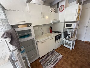 Eine kleine Küche mit weißen Schränken, einer Spüle, einer Mikrowelle und einer Kaffeemaschine.