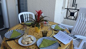 A dining table set with plates, cutlery, and a menu, surrounded by chairs. - 2P/Mezzanine Apt 4 Pers in Saint-Aygulf - Terrace, Parking, Washing Machine (Saint-Aygulf)