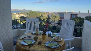 Una mesa redonda con mantel amarillo, sillas blancas y vista a un paisaje costero.