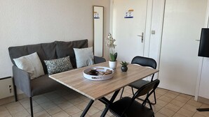 Una habitación pequeña con sofá, mesa y televisor.