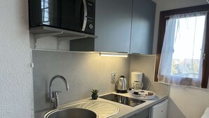 Una kitchenette compacta con un lavamanos de acero inoxidable, una cafetera y una pequeña planta en maceta.