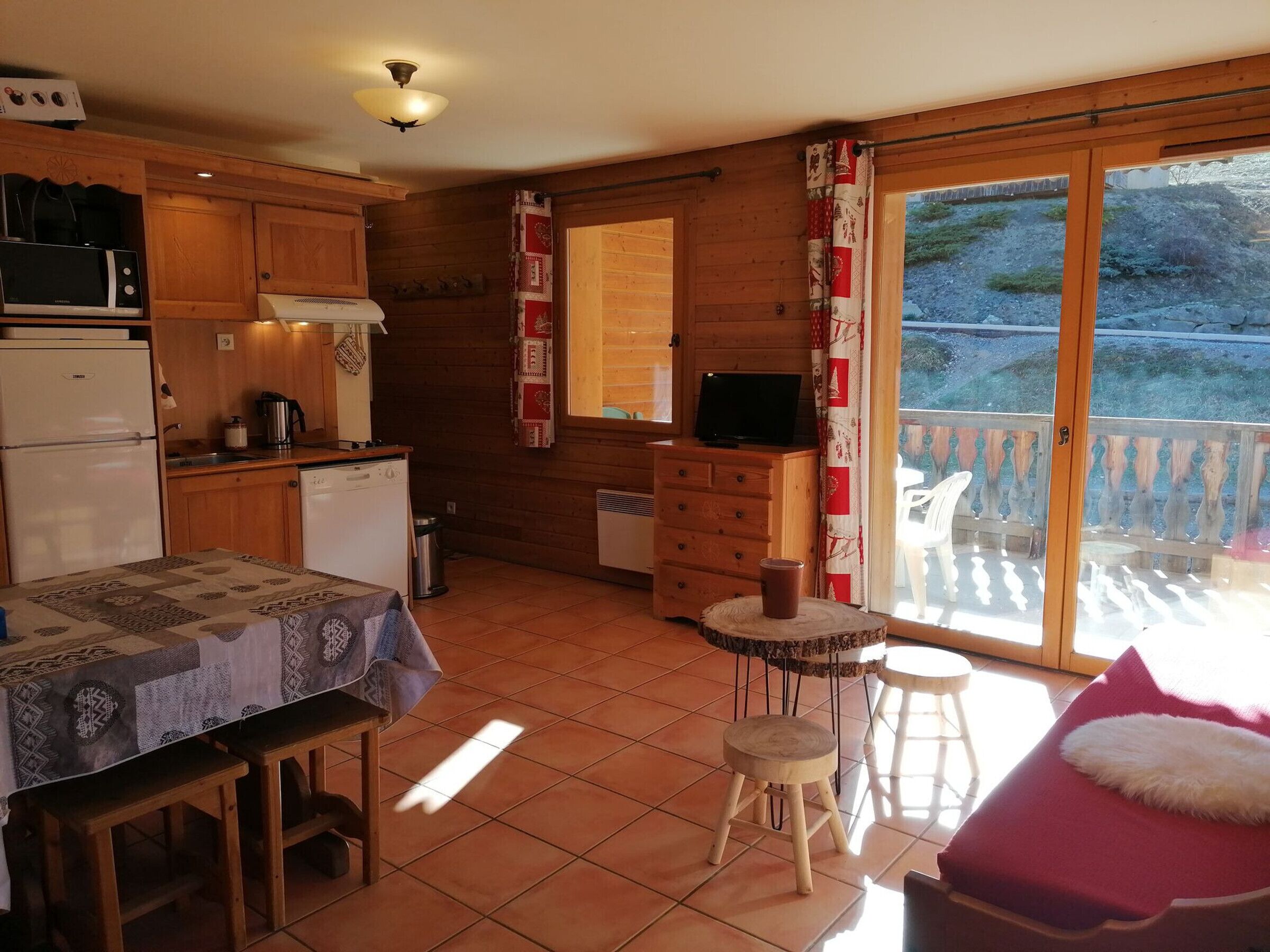 A cozy kitchen with wooden cabinets, a dining table, and a TV on a dresser.