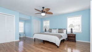 A bedroom with a bed, a ceiling fan, and a nightstand.