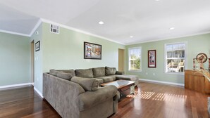 A spacious living room with hardwood flooring, a sectional sofa, and a wooden coffee table.