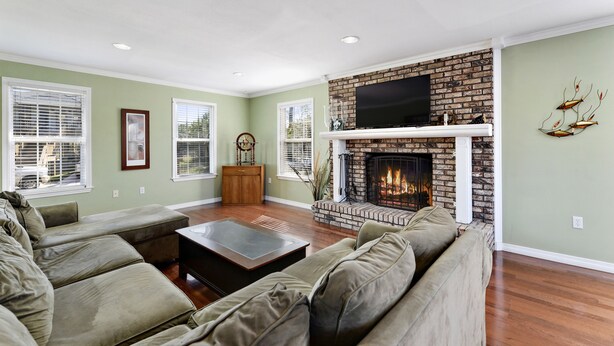 A living room with a fireplace, green walls, and a large window.