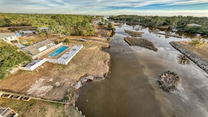A residential area with a swimming pool, a small dock, and a river.