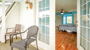 A room with a wooden floor, a bed with a blue cover, and a chair.