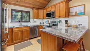 A modern kitchen with wooden cabinets, stainless steel appliances, and a granite countertop. - Woodlands 2 Bedroom & Loft Townhouse In A Beautiful Wooded Complex (Mammoth Lakes)