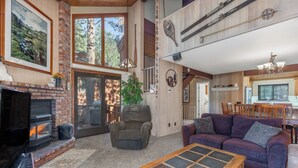 A cozy living room with a fireplace, comfortable seating, and a dining area. - Woodlands 2 Bedroom & Loft Townhouse In A Beautiful Wooded Complex (Mammoth Lakes)