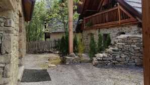 A rustic stone building with a wooden porch and a stone wall. - Charming 5-person mazot, renovated in Pra Loup, quiet hamlet (Pra-Loup)