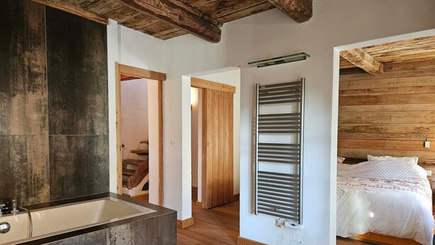 A modern bathroom with a large bathtub, wooden beams on the ceiling, and a wooden floor. - Charming 5-person mazot, renovated in Pra Loup, quiet hamlet (Pra-Loup)