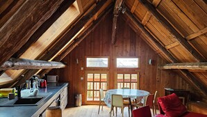 A cozy wooden cabin with a kitchen, dining area, and a red sofa. - Charming 5-person mazot, renovated in Pra Loup, quiet hamlet (Pra-Loup)