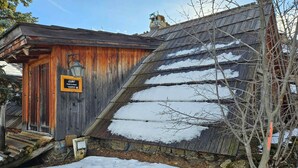 A rustic wooden building with a sloped roof covered in snow, a wooden door, and a signboard. - Charming 5-person mazot, renovated in Pra Loup, quiet hamlet (Pra-Loup)