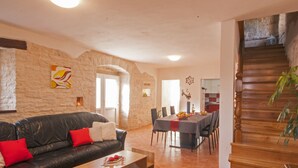 Un salón amplio con un sofá de cuero, una mesa de comedor y una escalera que lleva a un nivel superior.